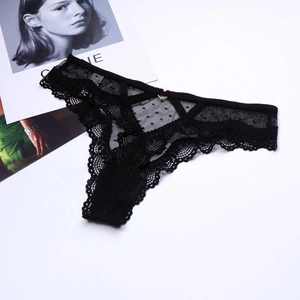 Détail d'un string en dentelle noire à pois avec anneau en métal cœur doré