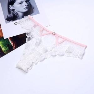 Détail d'un string en dentelle blanche avec bretelles roses et anneau coeur en or rose