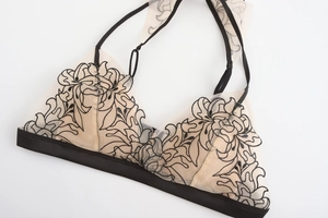 Detail of sheer mesh triangle bra with intricate black floral embroidery and adjustable straps