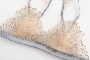 Dettaglio del ricamo floreale grigio su tessuto a rete di un reggiseno senza ferretto