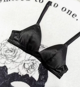 Detail of minimalist black silk triangle bralette showing smooth satin texture and fine stitching
