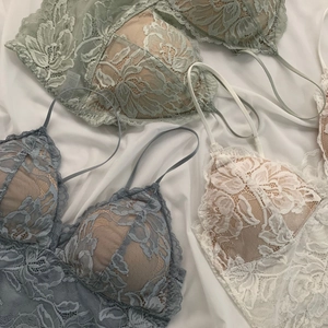Detailed flat lay of three lace triangle bralettes in sage green, blue and ivory white