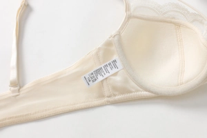 Detailed macro view of cream lace bra interior with cotton lining and mesh side wings