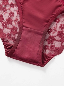 Detalle de ropa interior de encaje burdeos con motivos florales y refuerzo de algodón suave