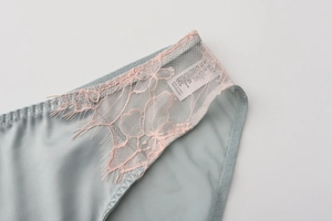 Detail of light blue satin panties with pink eyelash lace and product care label