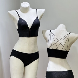 Detail of black glitter lingerie set featuring front gold zipper and strappy crisscross back