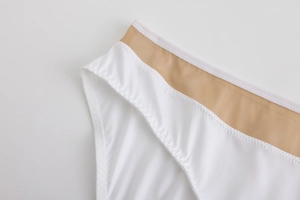 Detail eines nahtlosen weißen BHs mit khakifarbenem Netzbund und Zickzack-Nähten
