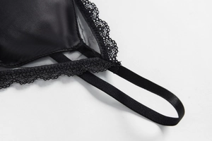 Detailed close-up of intricate black lace floral patterns on satin lingerie fabric