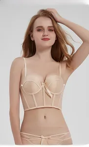 Detalle del bustier de malla beige con aros suaves y un elegante lazo decorativo