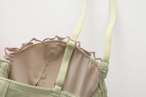 Dettaglio del reggiseno a corsetto verde chiaro con pizzo rosa e fibbie in metallo dorato