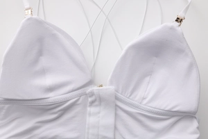 Detail of white triangle bra showing golden buckles and intricate cross straps