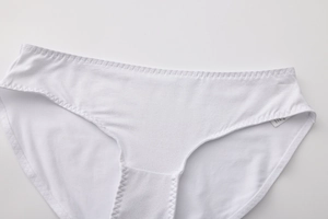 Detailed close-up of white cotton panties featuring elastic waistband and zigzag stitching