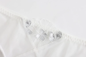 Close-up of white lace lingerie with silver floral embroidery and breathable mesh details