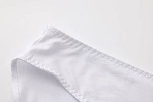 Detail view of white lace lingerie showing high-quality stitching and elastic fabric texture