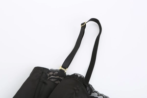 Dettaglio ravvicinato del reggiseno in raso nero con pizzo e fibbie in metallo dorato