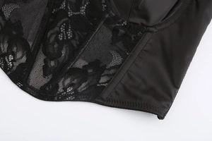 Dettaglio macro di pizzo floreale nero e corsetto in raso con stecche di sostegno