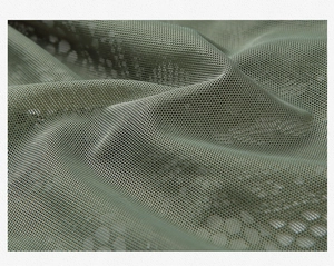 Vue détaillée du tissu en dentelle verte avec une texture en maille fine et légère