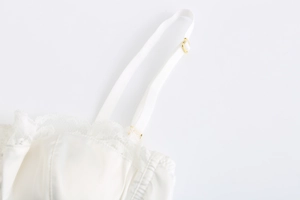 Dettaglio del reggiseno in raso bianco e pizzo con fibbie in metallo dorato regolabili