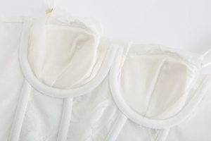 Dettaglio del corsetto in pizzo bianco con supporto a stecche e tessuto mesh