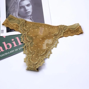 Detail of ginger yellow lace thong featuring delicate floral embroidery and dot mesh fabric