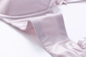 Close-up of silky high-stretch fabric and neat stitching on pink lace bra side wings