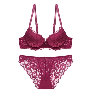Detailed macro view of burgundy lace bra set with floral patterns and delicate pendant