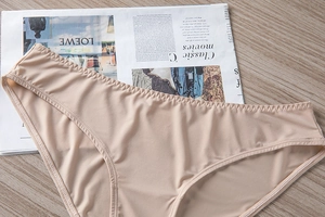 Bragas de seda color nude de talle alto con costuras onduladas en mesa madera