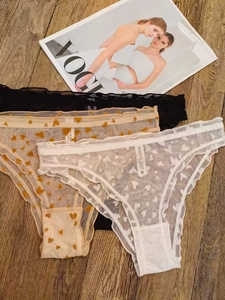 Detailed shot of three lace panties with heart prints on rustic wooden background