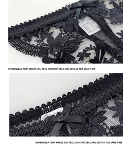Detail van zwarte kanten slip met bloemenborduursel en een satijnen strikje erop