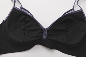Gros plan du soutien-gorge en dentelle noire avec coutures violettes et détails brodés