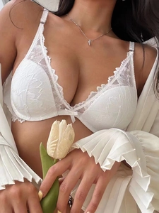 Macro shot of French white lace bra featuring delicate scalloped edges and bow detail