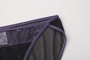 Detalle de encaje floral púrpura y malla negra en bragas transpirables de tiro bajo