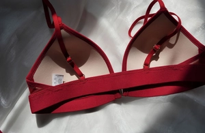 Primer plano del interior del bralette rojo con forro beige y etiqueta de talla