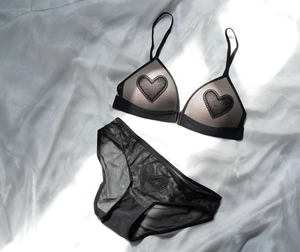Detalle de conjunto de lencería de encaje negro con apliques de corazón en seda