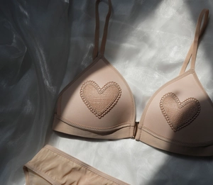Detalle de conjunto de bralette de encaje con cierre frontal sobre fondo de seda blanca