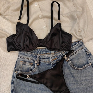 Détail d'un ensemble de lingerie en satin noir avec boucles en strass sur fond de denim