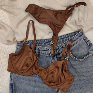 Détail du soutien-gorge en satin chocolat avec boucles en X en cristal sur les bretelles
