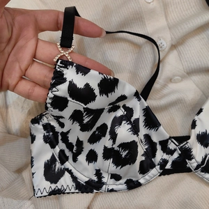 Détail d'un soutien-gorge satiné imprimé animal avec boucle X dorée en strass
