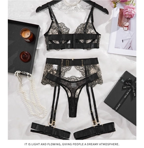 Flat lay of black floral eyelash lace lingerie set with suspenders and gold buckles