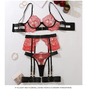 Detail of red floral lace embroidery and black straps on a 4-piece lingerie set