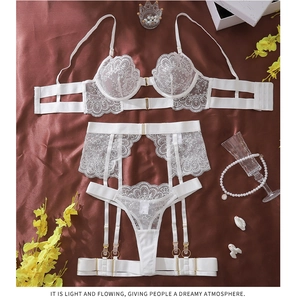 Detailed view of white floral eyelash lace lingerie set with garters on satin background