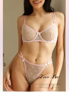 Detalle de conjunto lencería rosa claro con encaje de lunares y lazos blancos finos
