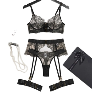 Black lace lingerie set with floral embroidery, garter belts, and gift box on white background