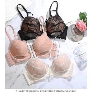 Dettaglio di reggiseni in pizzo floreale in nero, rosa e crema su fondo di marmo