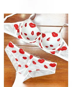 Set lingerie in pizzo bianco con ricamo a labbra rosse su pavimento in legno scuro