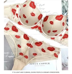 Dettaglio ricamo labbra rosse e pizzo dorato su completo intimo color champagne