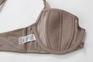 Detail of sheer mesh bra cup with vertical seams and care label in coffee brown