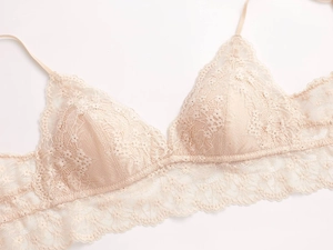 Detalle de bordado de encaje delicado en el bralette triangular en tono albaricoque