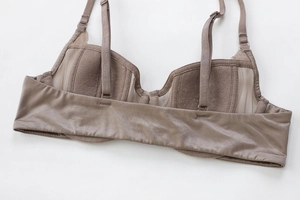 Macro detail of breathable mesh fabric and adjustable silk-like straps on a brown bra