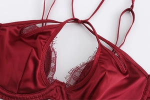 Macro detail of wine red satin lingerie with delicate eyelash lace trim and straps